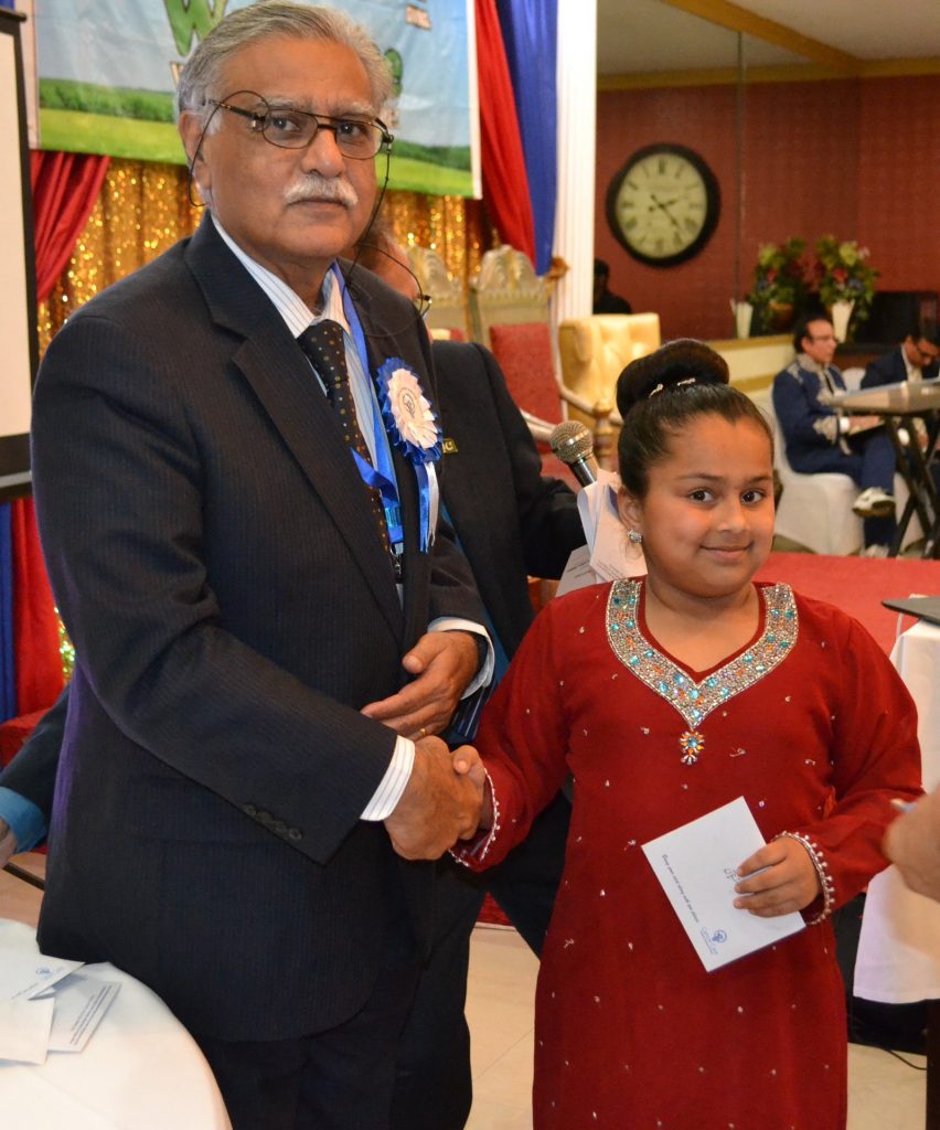 A young Pakistani-American girl presenting a donation to Dr Shahryar 